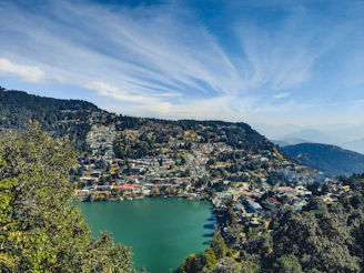 a lake surrounded by trees and mountains under a blue sky