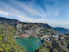 a lake surrounded by trees and mountains under a blue sky