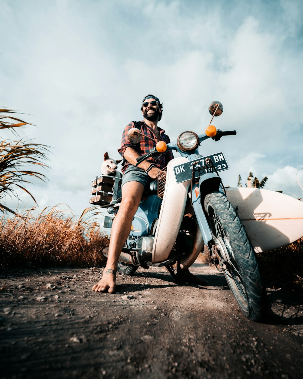 a man sitting on a motorcycle on a dirt road