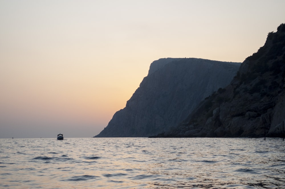 a boat is in the water near a cliff