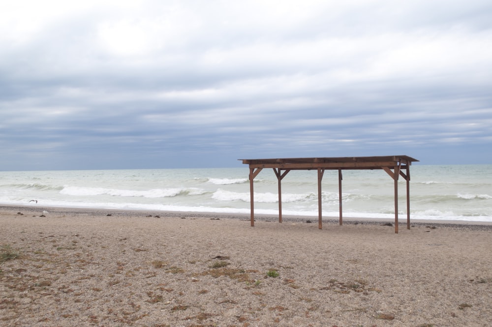 a gazebo sitting on top of a sandy beach next to the ocean