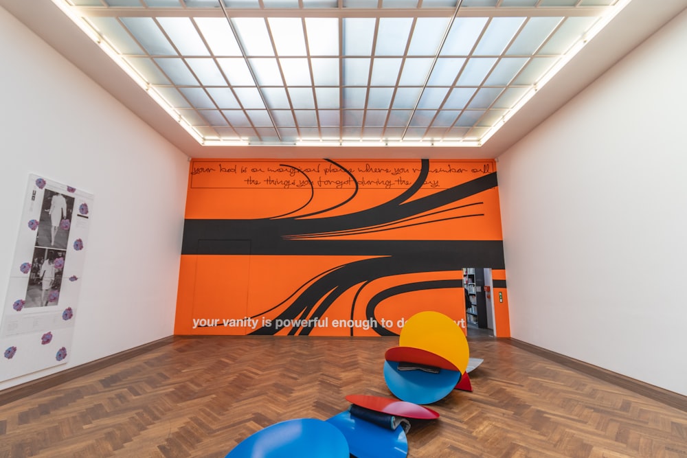 a room with a large orange wall and a painting on the wall