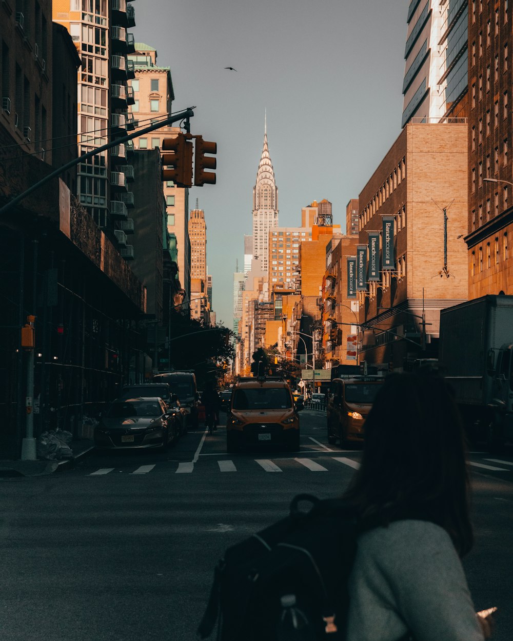 a woman walking across a street next to tall buildings