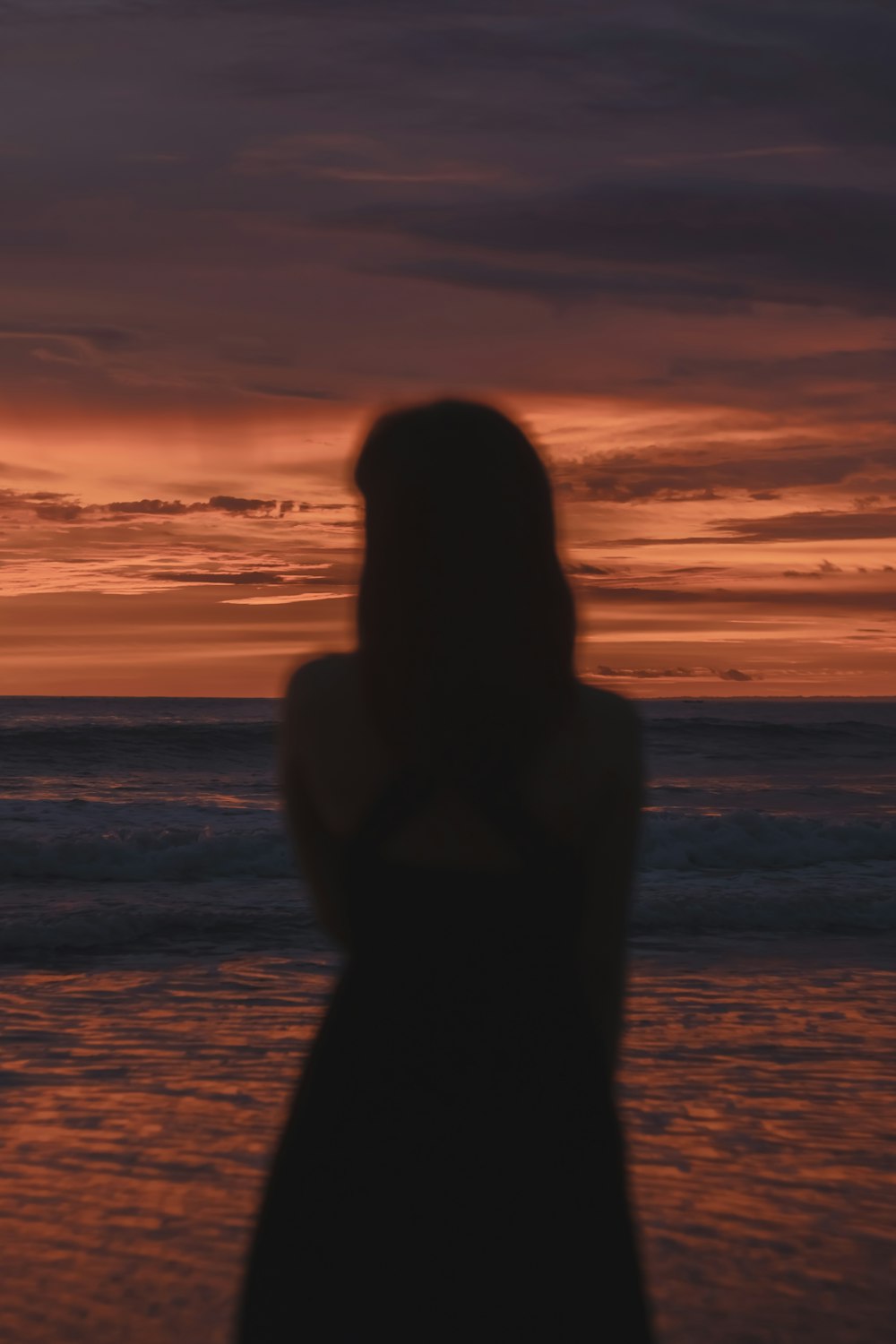 a woman standing on top of a beach next to the ocean