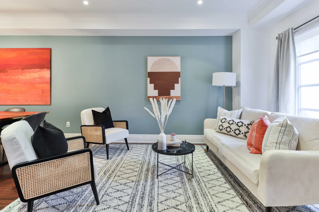 Sala de estar com tapete padronizado, cortinados e sofá claro
