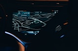 A car dashboard with a high-tech navigation system displayed clearly on a sleek touchscreen, showing detailed maps and directions in a low light environment. The interface has a modern and futuristic design with various navigation options visible.