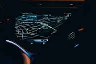 A car dashboard with a high-tech navigation system displayed clearly on a sleek touchscreen, showing detailed maps and directions in a low light environment. The interface has a modern and futuristic design with various navigation options visible.