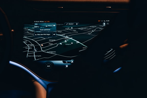 A car dashboard with a high-tech navigation system displayed clearly on a sleek touchscreen, showing detailed maps and directions in a low light environment. The interface has a modern and futuristic design with various navigation options visible.