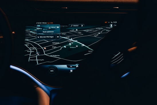 A car dashboard with a high-tech navigation system displayed clearly on a sleek touchscreen, showing detailed maps and directions in a low light environment. The interface has a modern and futuristic design with various navigation options visible.