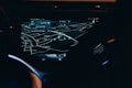 A car dashboard with a high-tech navigation system displayed clearly on a sleek touchscreen, showing detailed maps and directions in a low light environment. The interface has a modern and futuristic design with various navigation options visible.