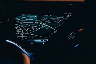 A car dashboard with a high-tech navigation system displayed clearly on a sleek touchscreen, showing detailed maps and directions in a low light environment. The interface has a modern and futuristic design with various navigation options visible.