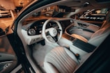 A luxurious car interior featuring high-end leather seats, a sleek dashboard with digital displays, and a stylish steering wheel with the Mercedes-Benz logo. The design is modern and sophisticated, with ambient lighting adding to the premium feel.