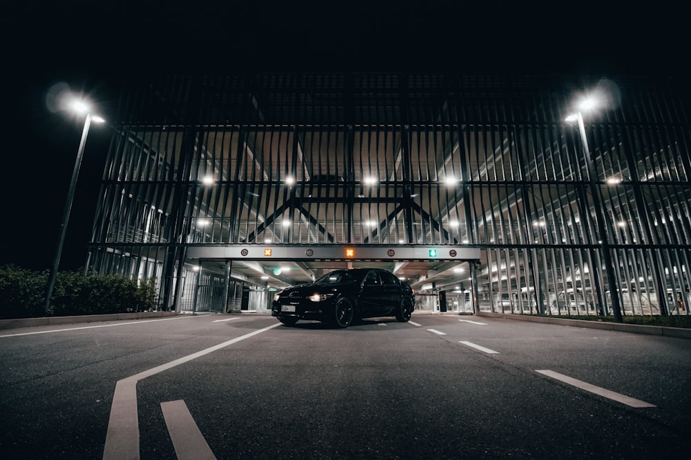 a black car driving down a street at night