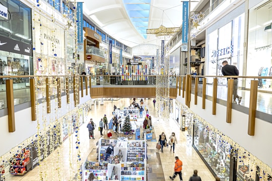 A bustling city centre mall with vibrant storefronts and shoppers.