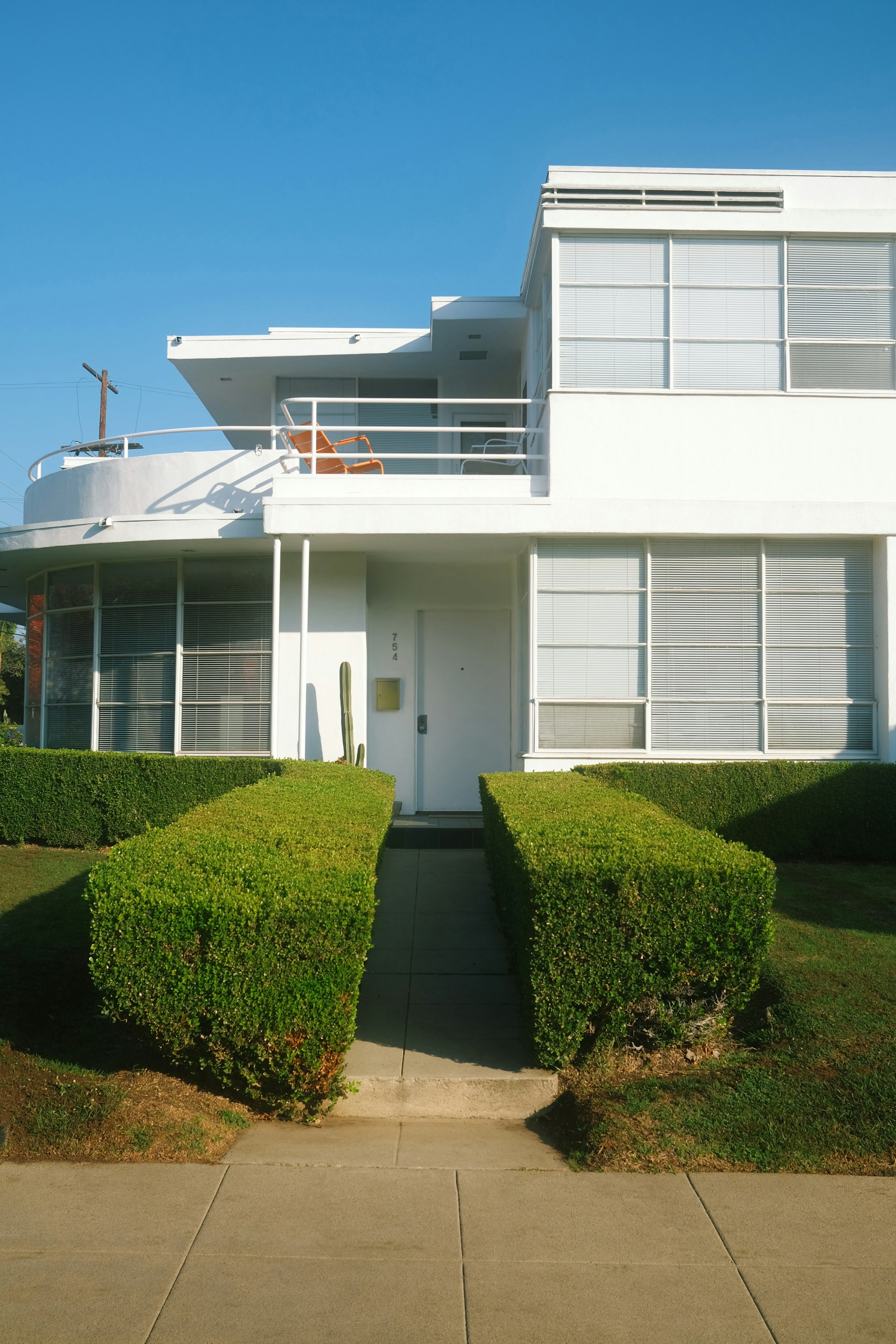 a white house with a white door and two hedges in front of it
