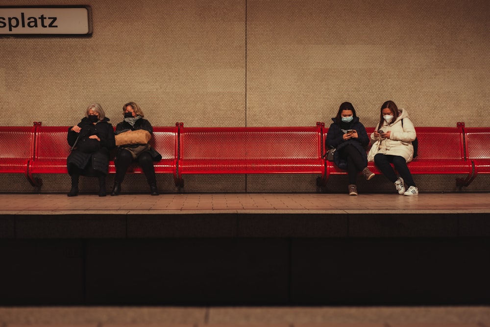 a group of people sitting on top of a red bench