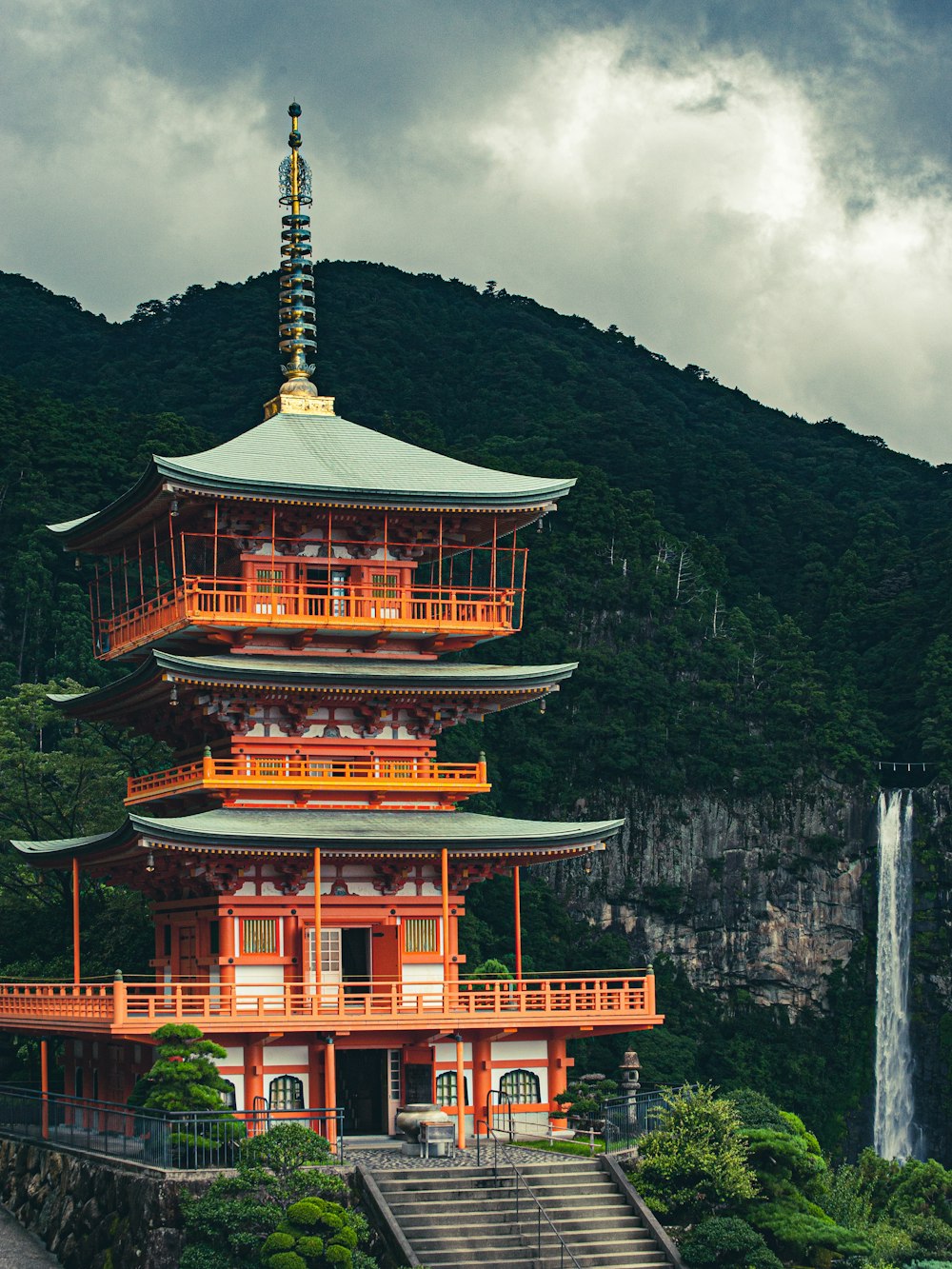 a tall pagoda with a waterfall in the background