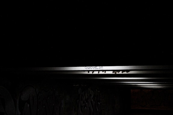 A moody, urban background with a graffiti wall featuring dark tones and a bright neon sign that says 'Contact Us'.