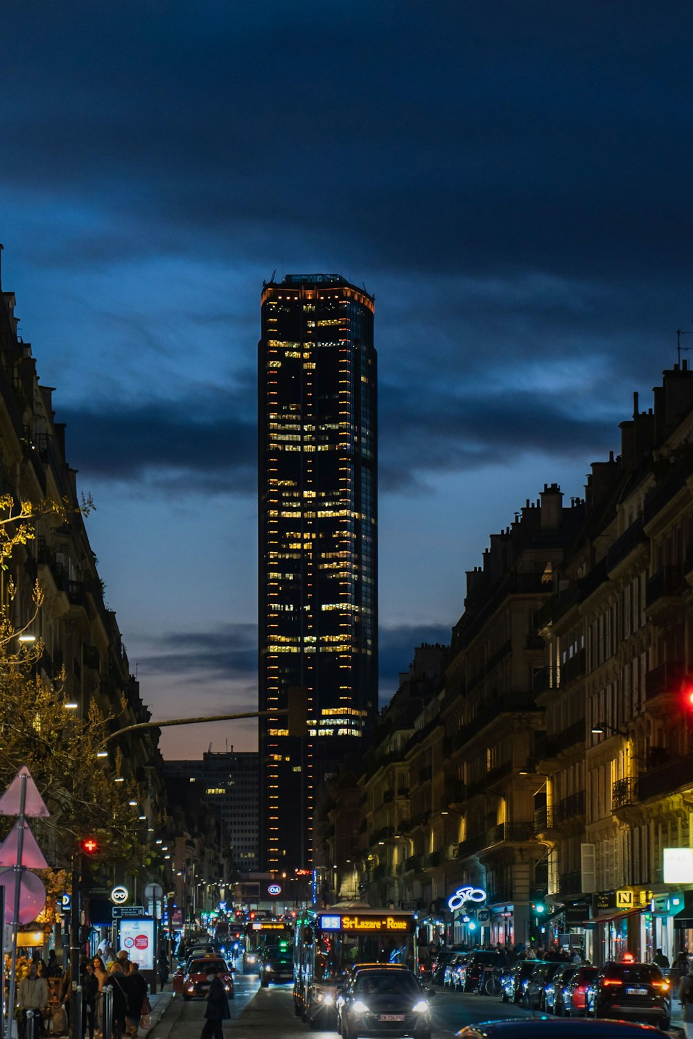 a city street at night with a tall building in the background