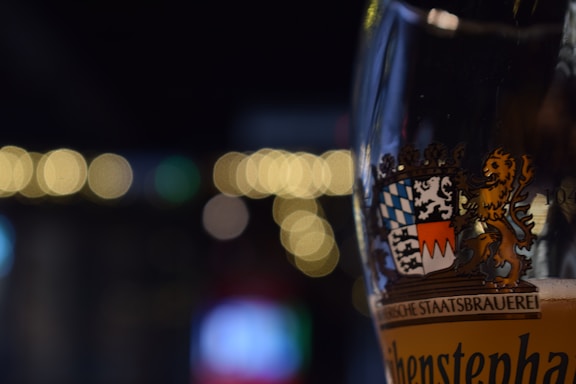 A close-up of a beer glass with a blurred background of a brewery.