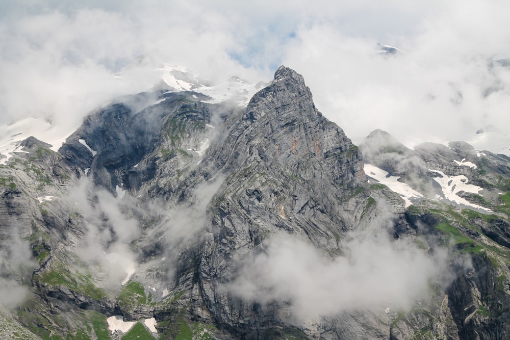 a very tall mountain surrounded by clouds in the sky