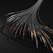 Numerous black cables or tubes with metallic and copper elements appear to be extending from a singular point, creating a fan-like spread. The cables have a textured spiral pattern, and the image has a dark, industrial aesthetic.