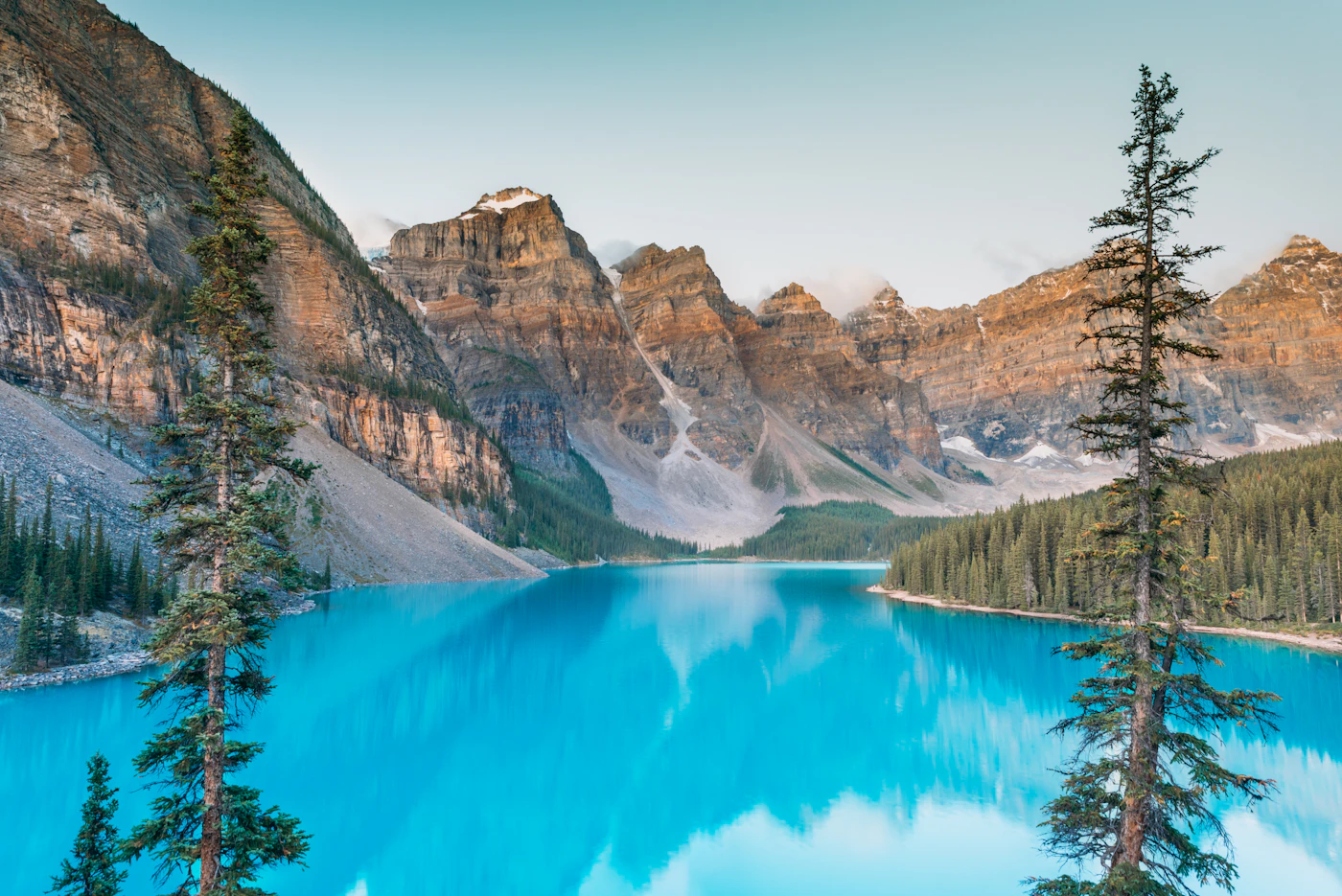 Moraine Lake at sunrise with calm turquoise water below the Valley of the Ten Peaks in Alberta
