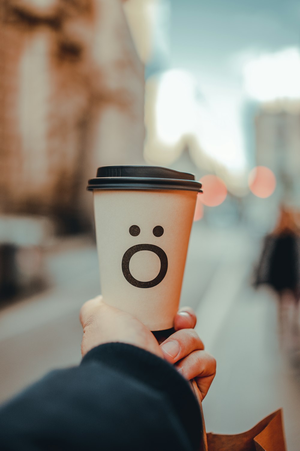 a person holding a coffee cup with a smiley face drawn on it