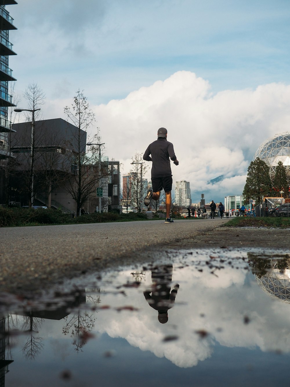 a man is running on a path near a puddle of water