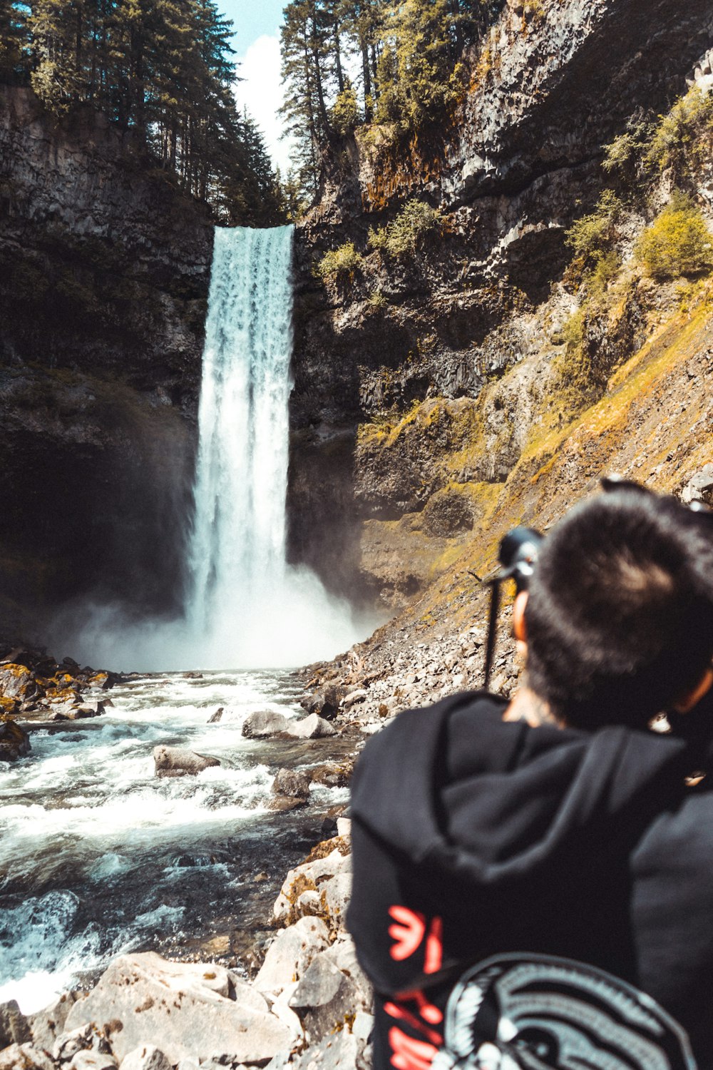 a man taking a picture of a waterfall