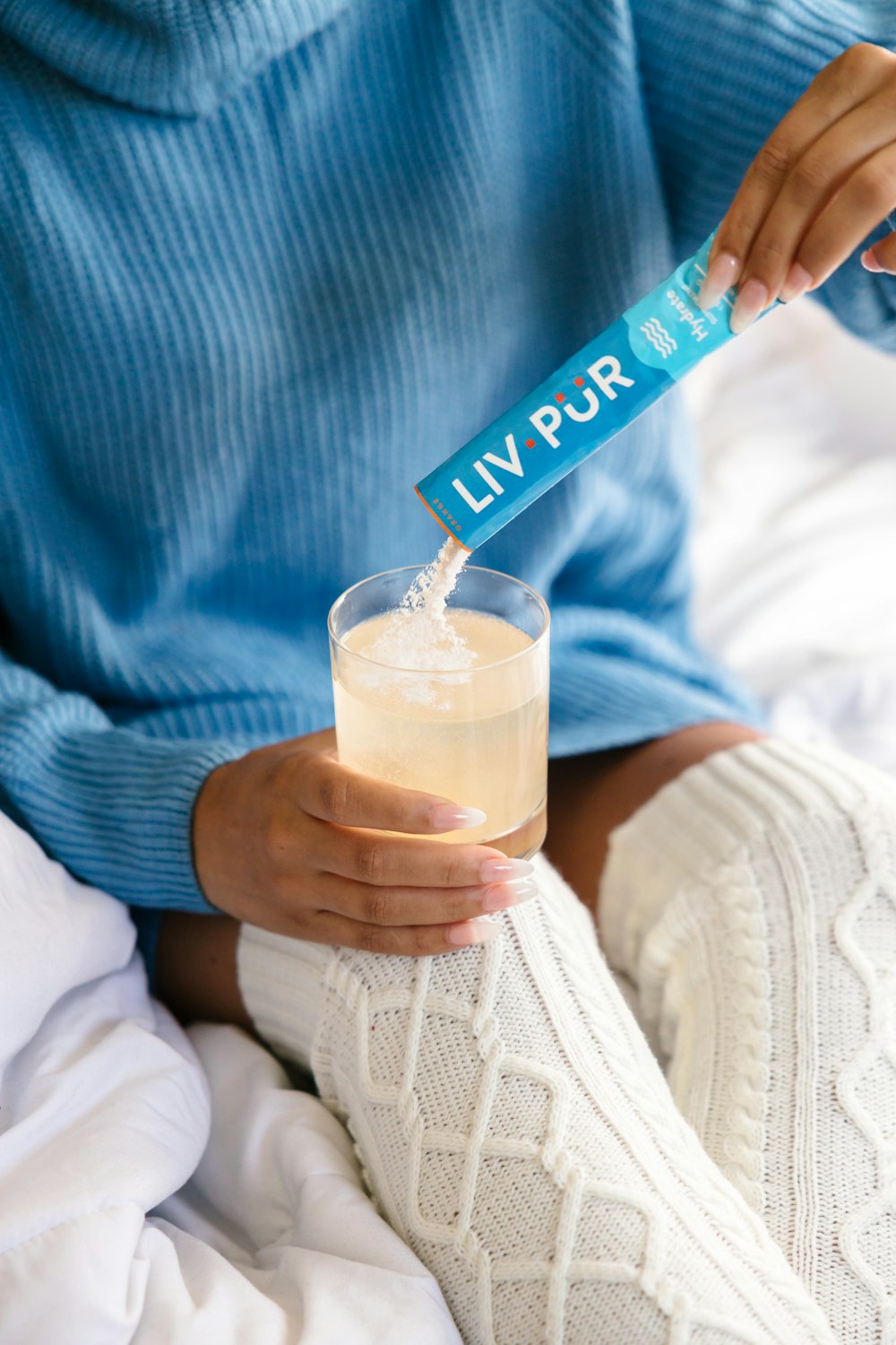 a person sitting on a bed holding a drink