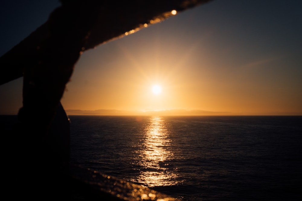 the sun is setting over the ocean as seen from a boat