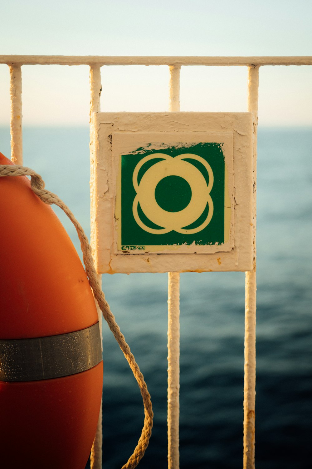 a life preserver attached to a metal fence next to the ocean