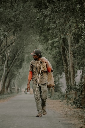a man walking down a tree lined road