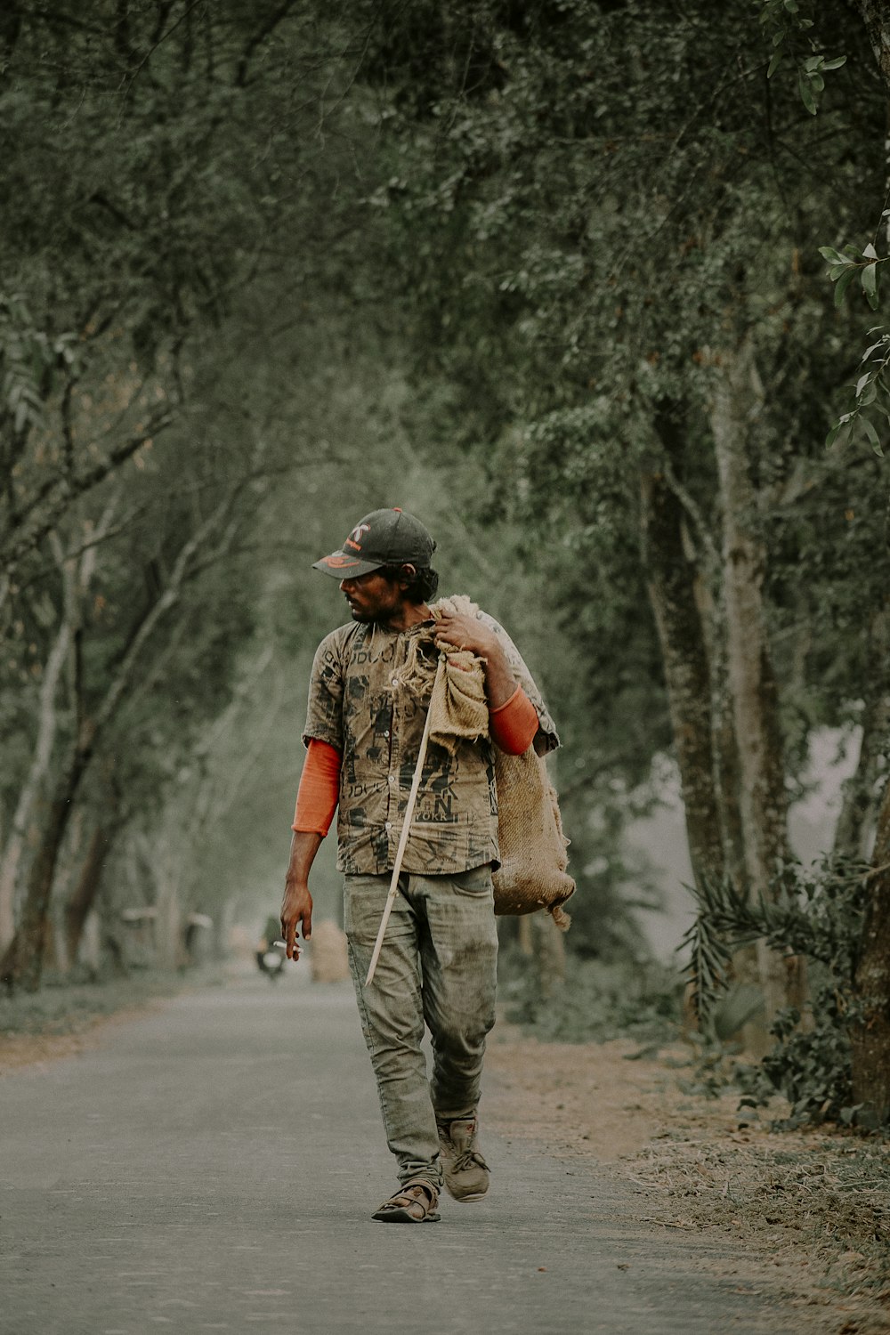 a man walking down a tree lined road