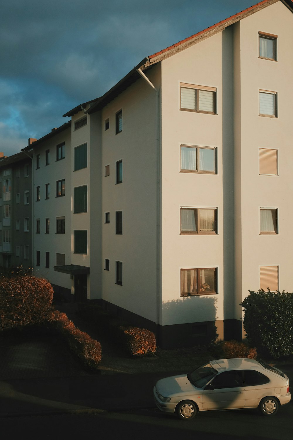 a white car parked in front of a white building