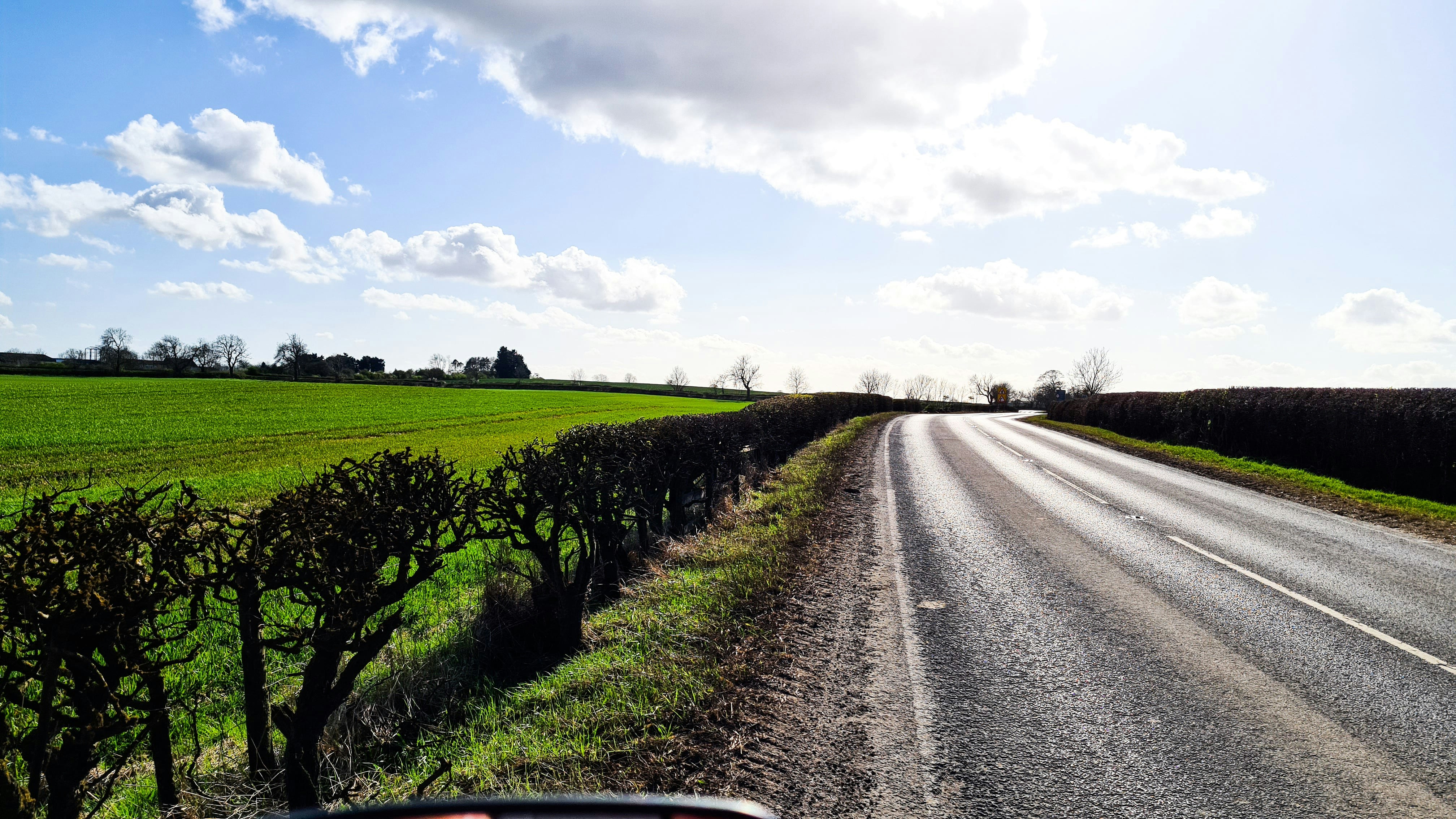 a car driving down a road next to a lush green field
