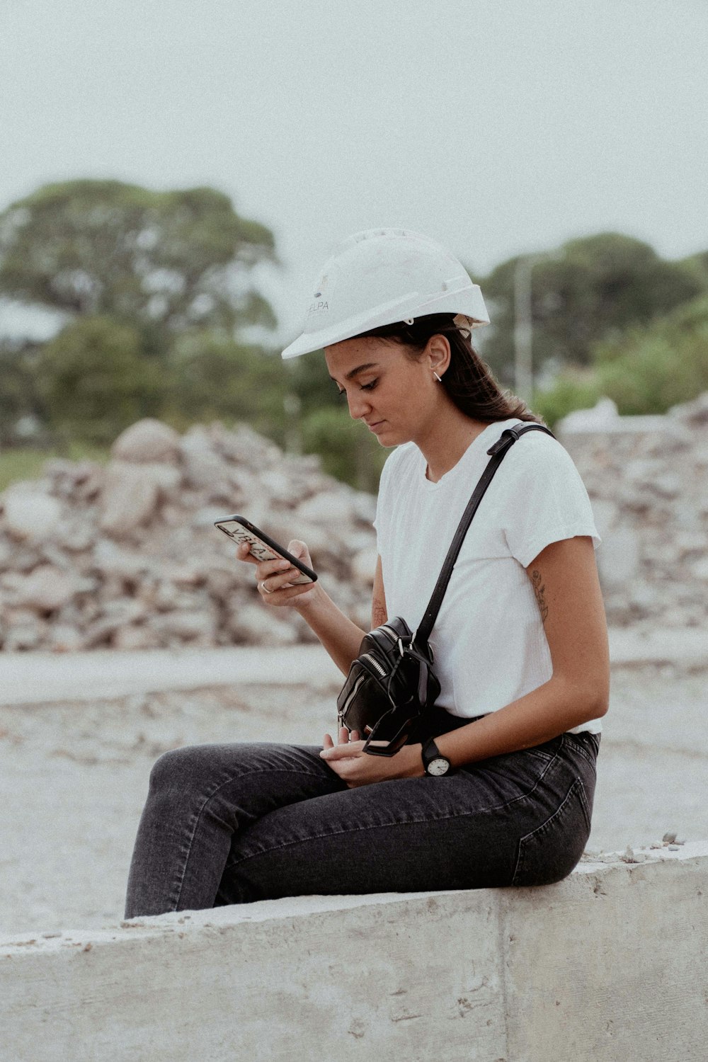 Una mujer sentada en una pared mirando su teléfono celular