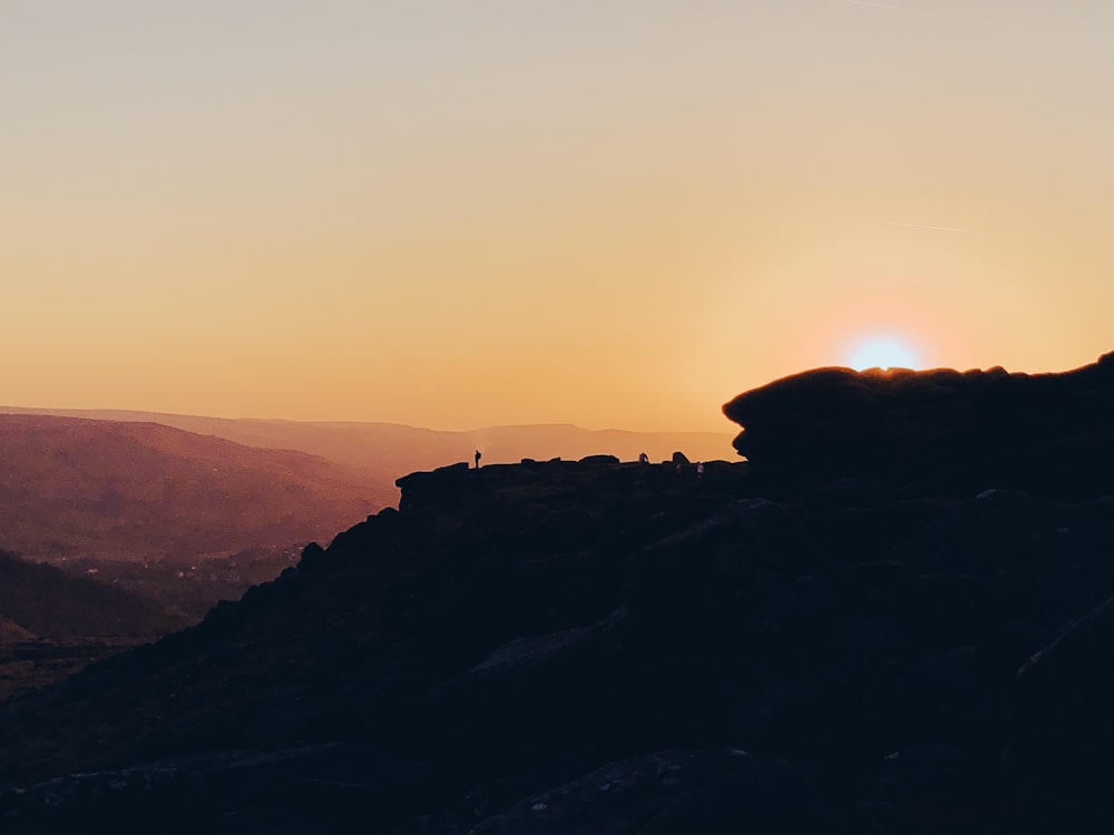 the sun is setting over a rocky mountain