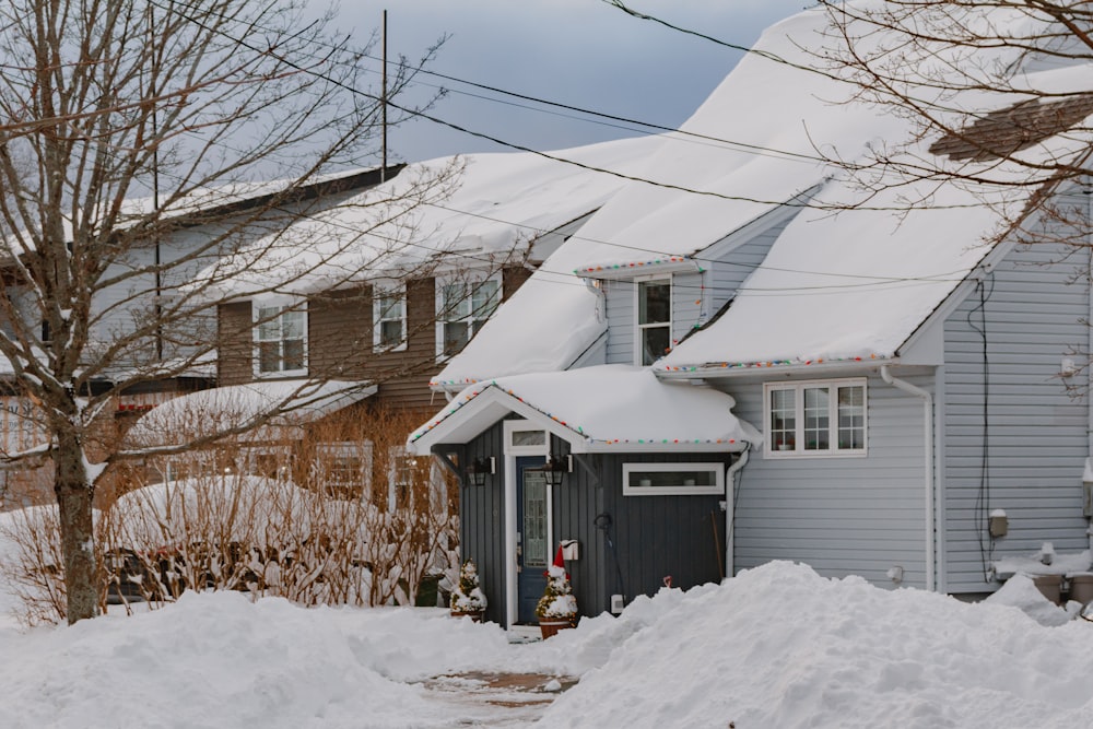 a house covered in snow next to a tree