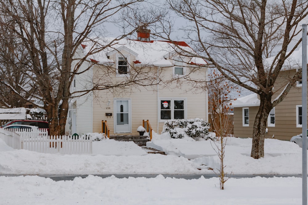 Una casa con nieve en el suelo y árboles frente a ella