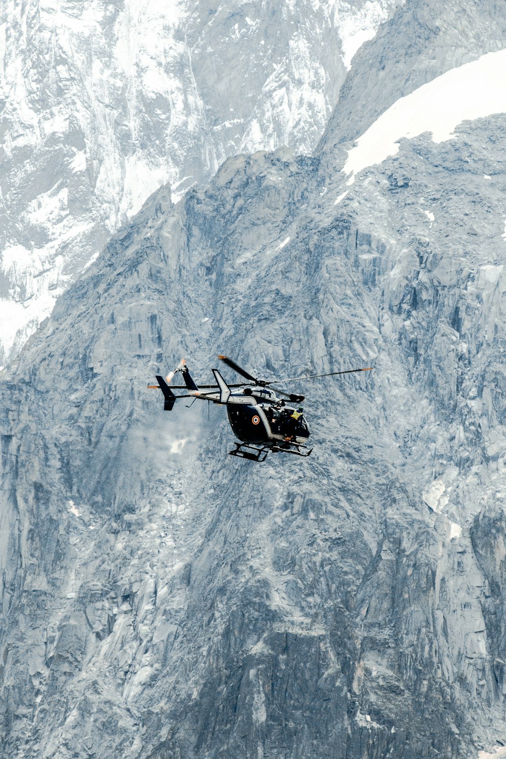 a black and white helicopter flying over a mountain