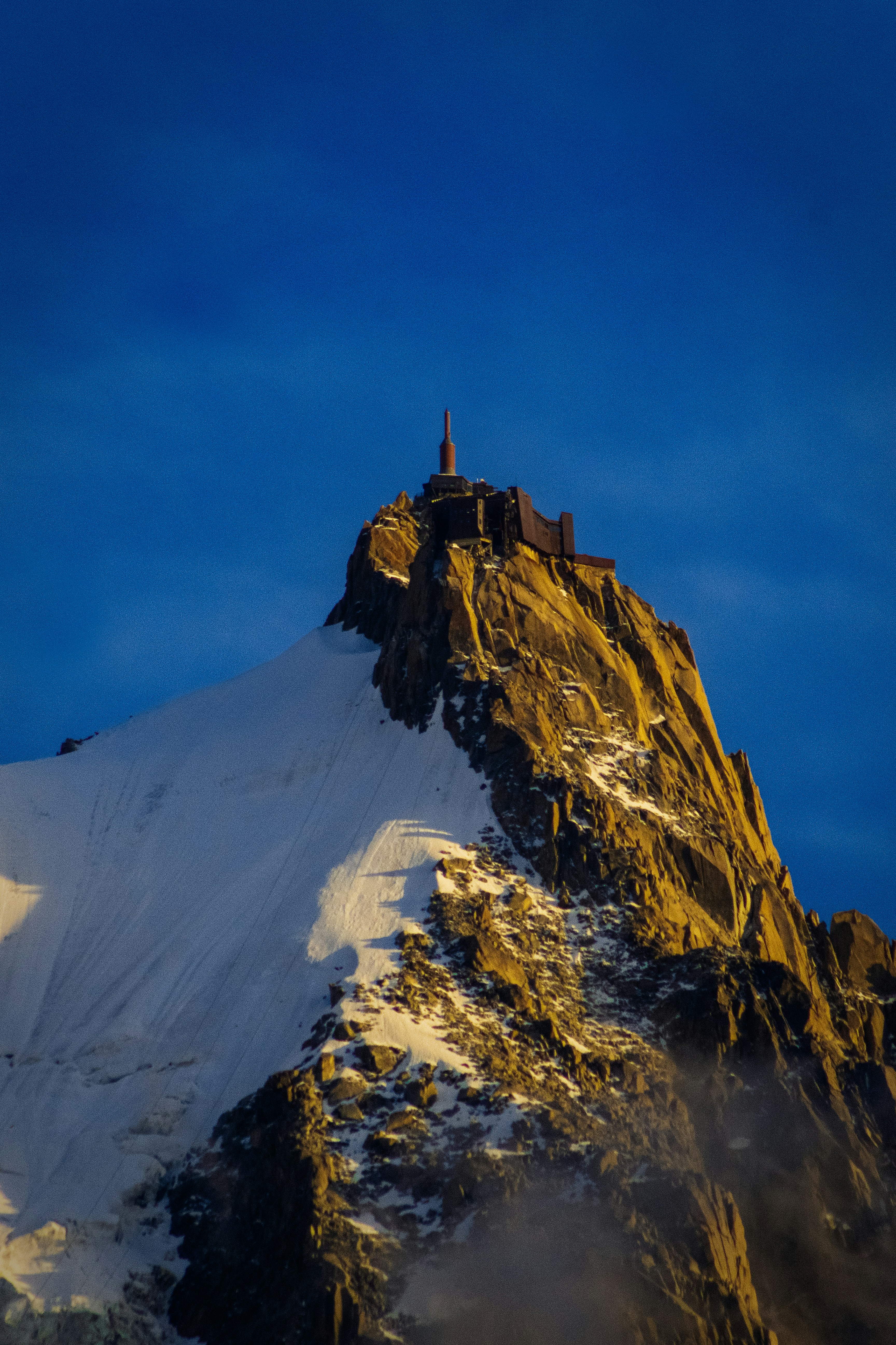 Una montagna innevata con una torre in cima