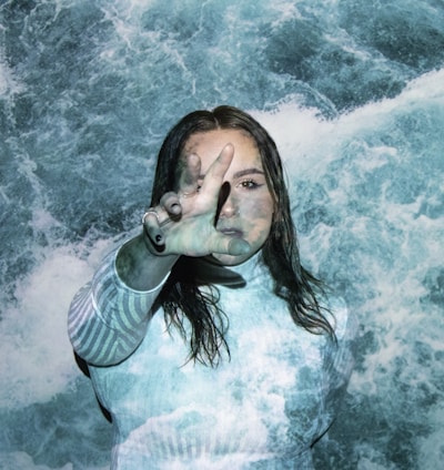 a woman is standing in the water with her hands in the air