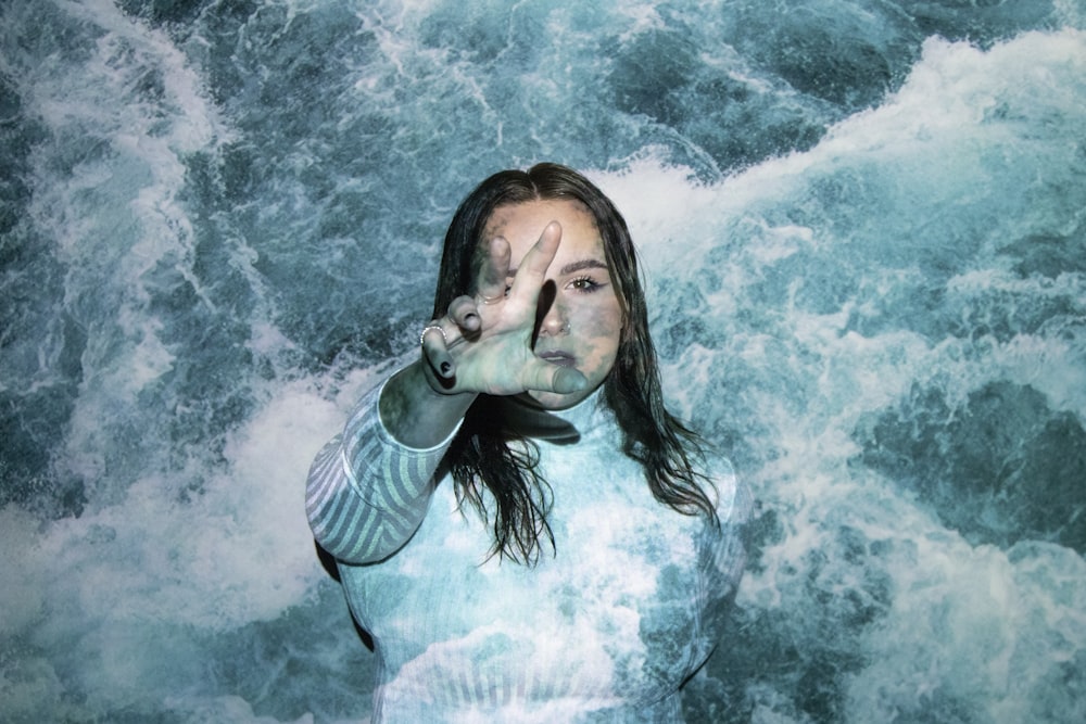 a woman is standing in the water with her hands in the air