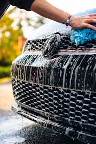 a person washing a black car with a blue rag