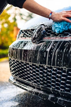 a person washing a black car with a blue rag