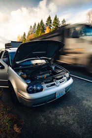 a car with its hood open on the side of the road
