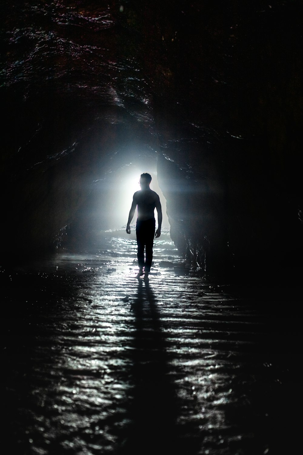 a man is walking through a dark tunnel