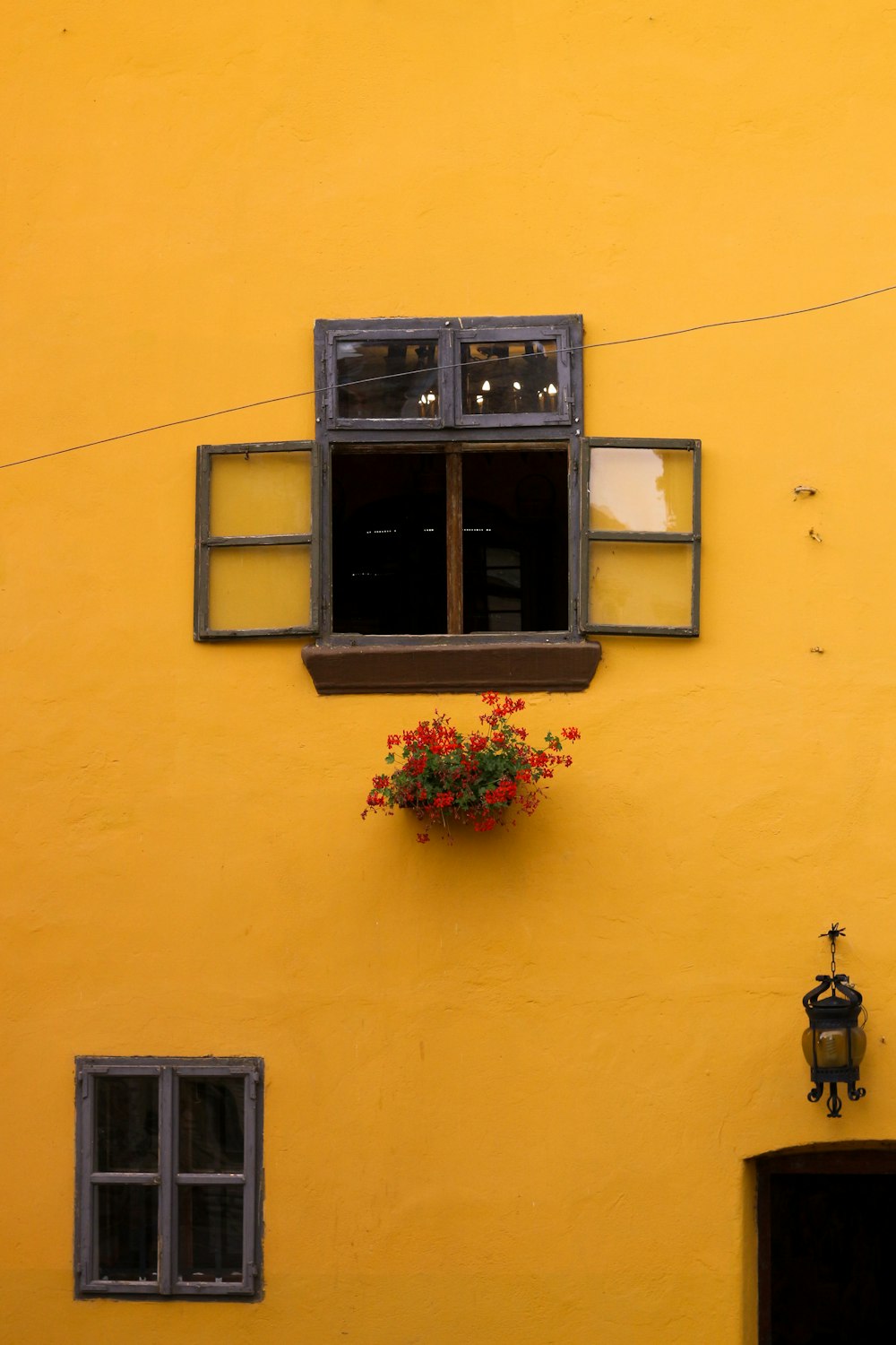 Un edificio amarillo con una ventana y una caja de flores
